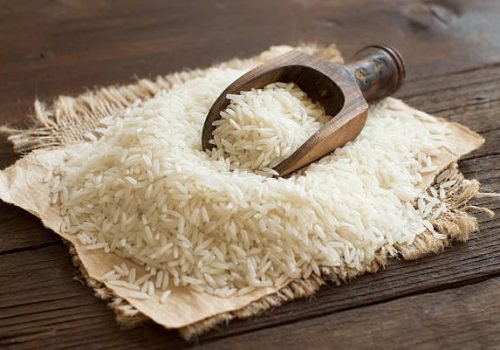 Pile of raw Basmati rice with a spoon close up
