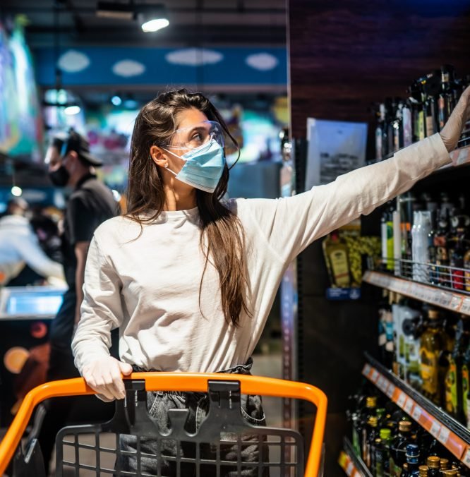 Woman with the surgical mask and the gloves is shopping in the supermarket after coronavirus pandemic. The girl with surgical mask is going to buy the some food.